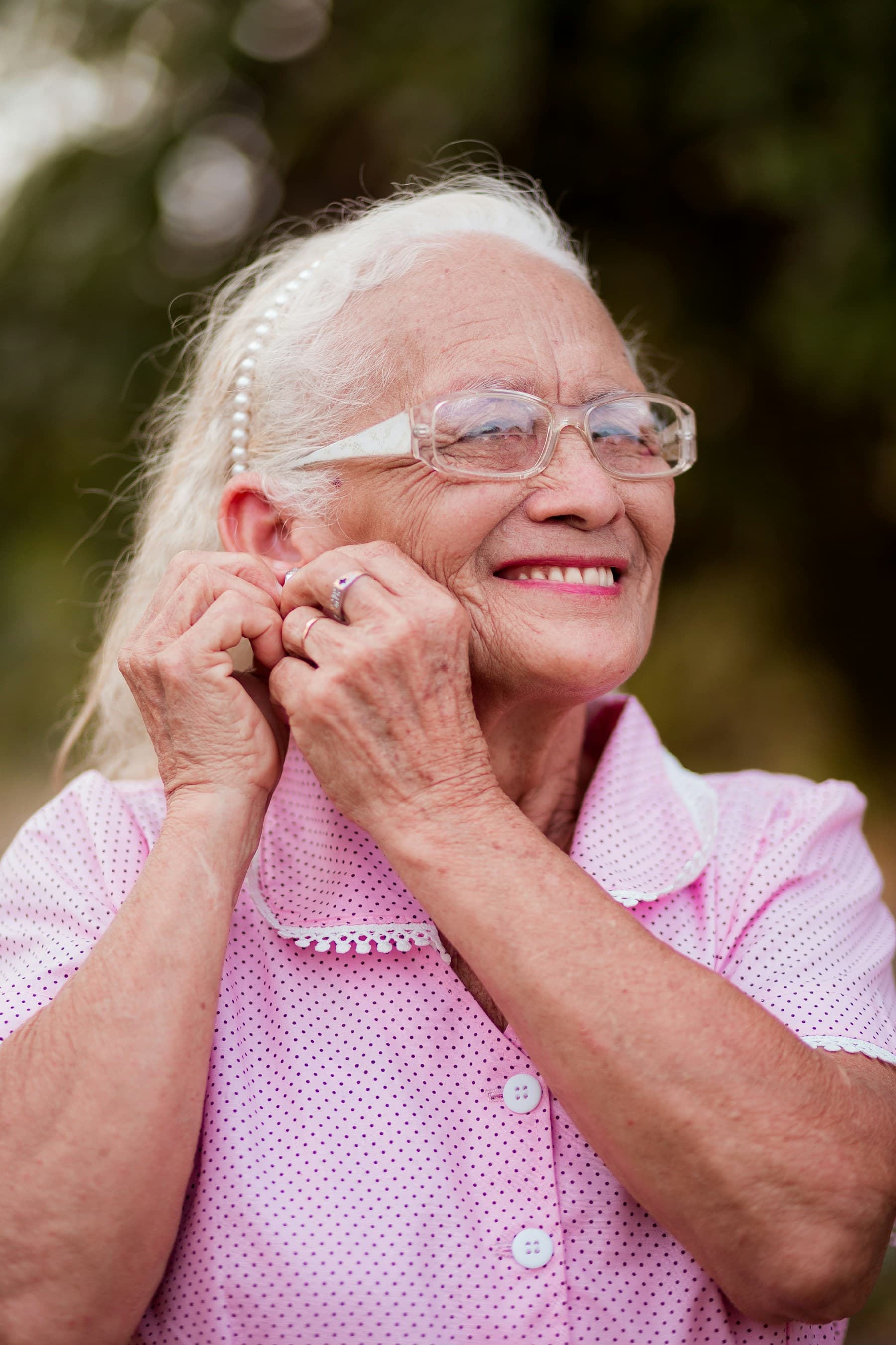 Senhora sorridente de cabelos brancos e camisa rosa
