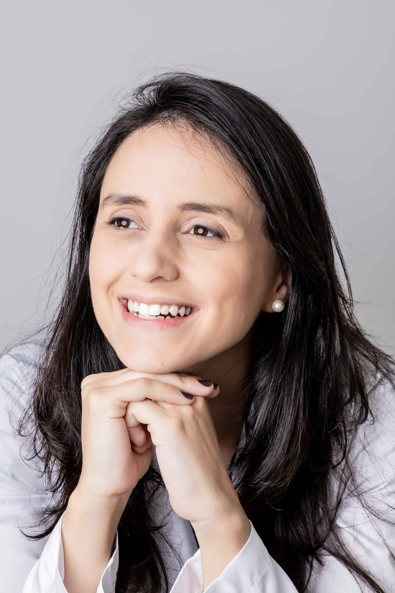 Retrato da Dra. Paula Azevedo, dermatologista, de jaleco e sorrindo